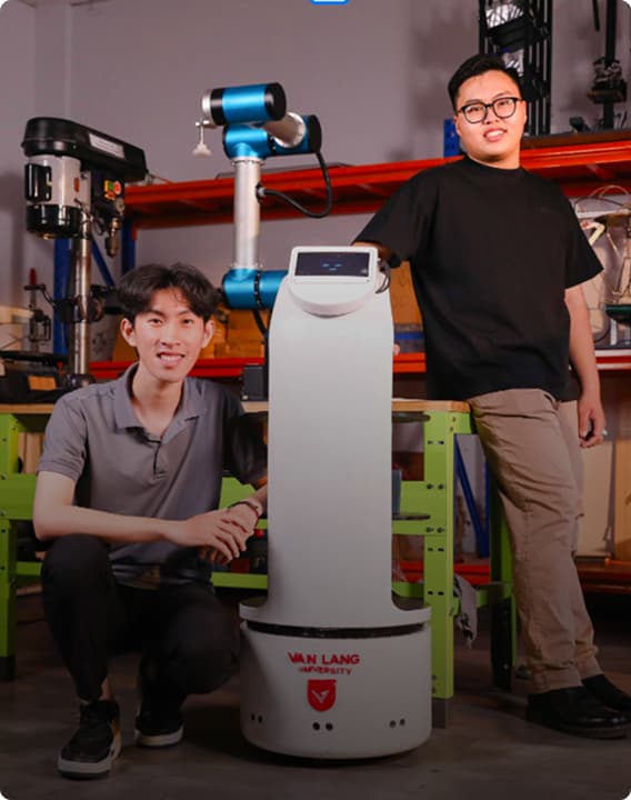 Two students standing beside a service robot
